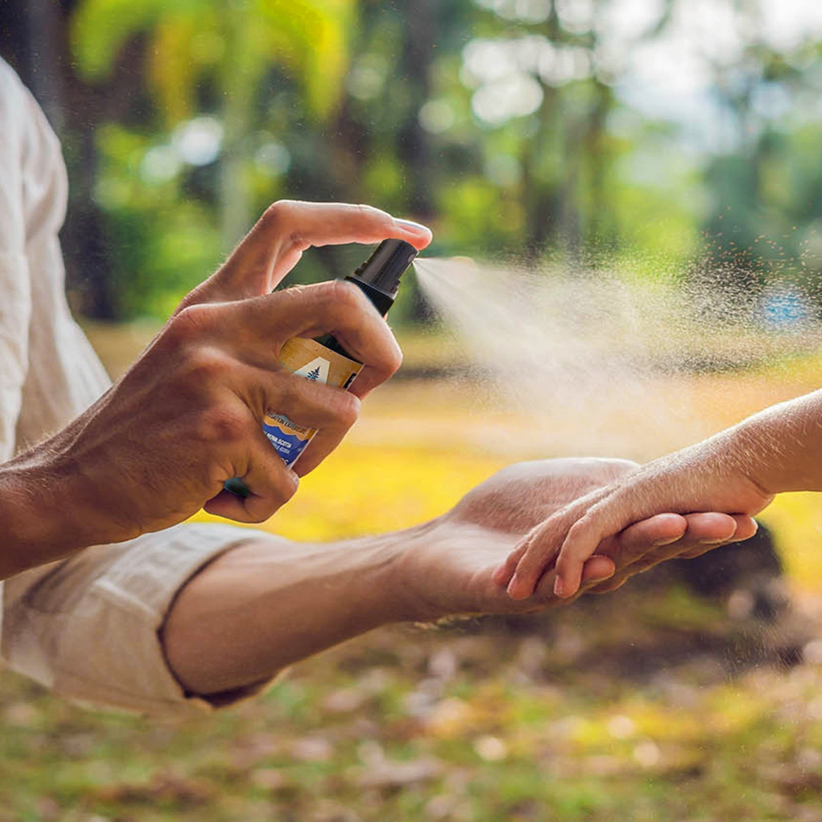 A parent’s hand spraying Tick Attack™ Botanical Insect Repellent onto a child's hand outdoors. A safe, natural, DEET-free tick repellent designed for families, providing protection for kids during outdoor activities.