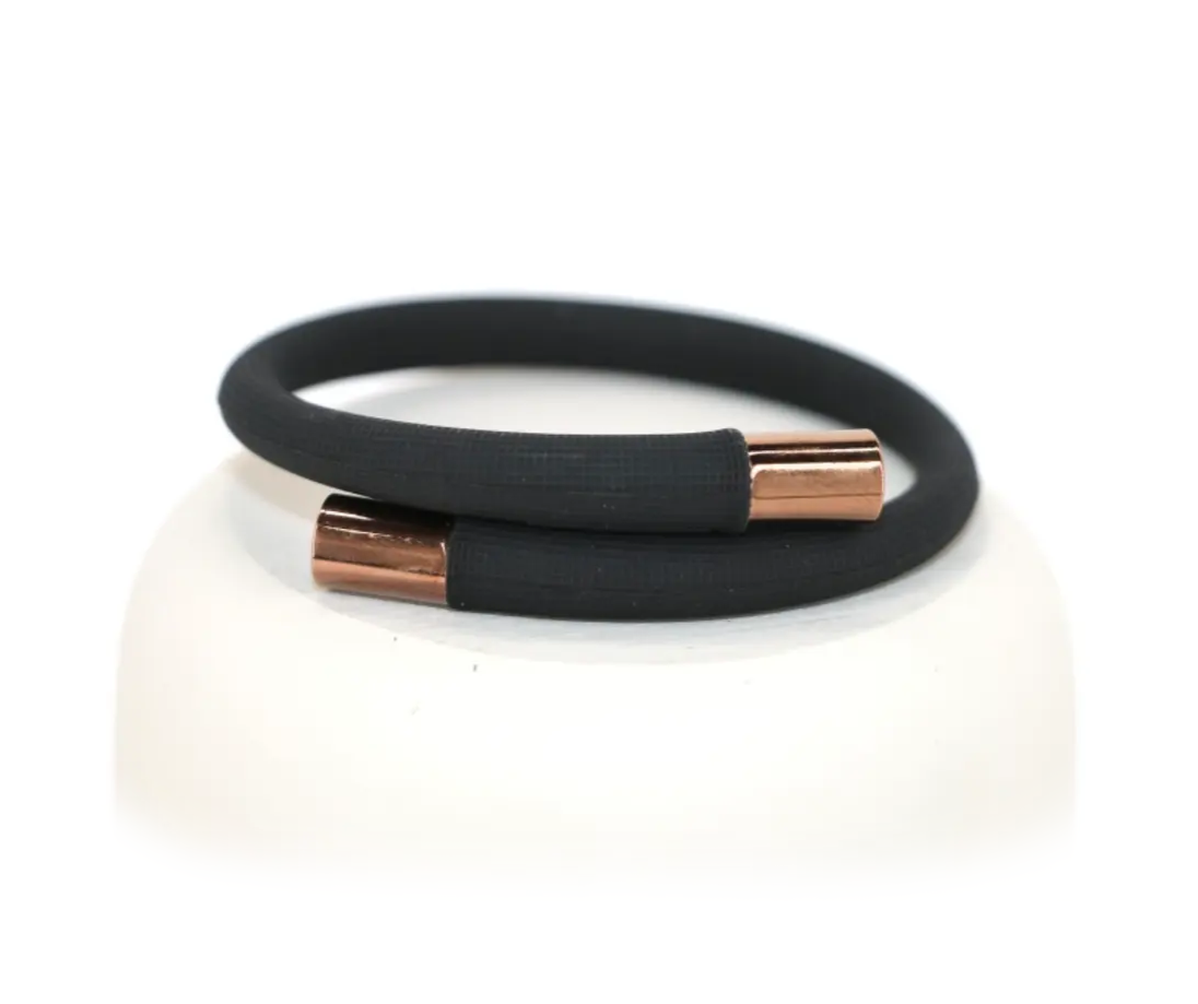 A sleek black silicone diffuser band with gold-plated metal caps, designed to hold AtlanTick Tick Attack™ Botanical Insect Repellent or other scents for long-lasting wear on the wrist or ankle.