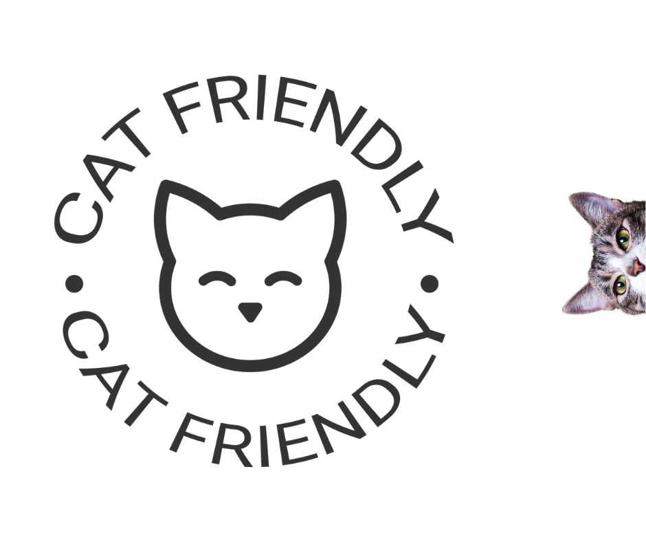 A "Cat Friendly" certification logo featuring a smiling cat face, encircled by the words "Cat Friendly" in a modern, minimalist font. A curious tabby cat peeks from the right side, reinforcing the feline-friendly theme.