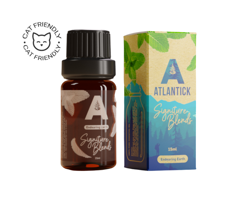 An amber glass bottle of AtlanTick's Endearing Earth Signature Blend alongside its eco-friendly, nature-inspired packaging. The label highlights Catnip and Cedarwood essential oils, and the box features mint leaves and woodland imagery. A "Cat Friendly" badge emphasizes its pet-safe formulation.